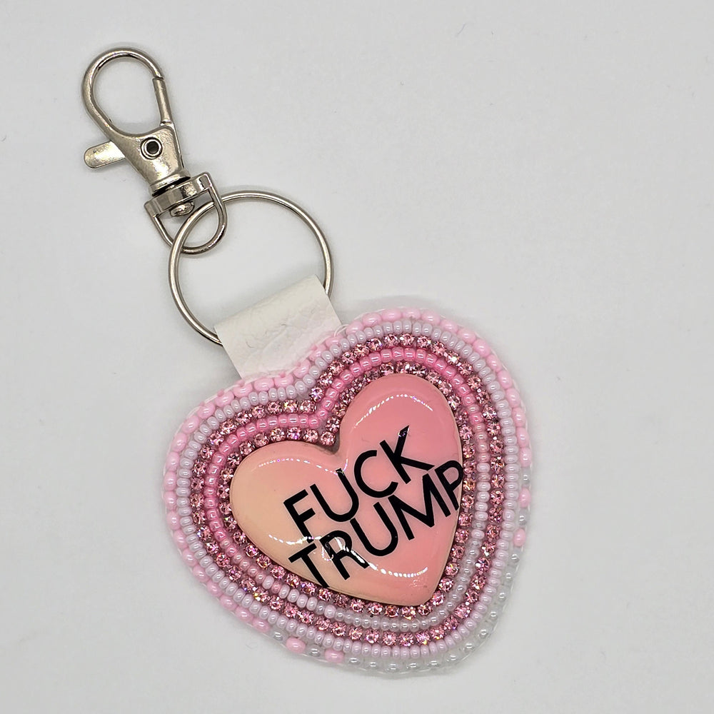 Heart-shaped keychain with beaded border and 'UCK YOU' text on a light gray background