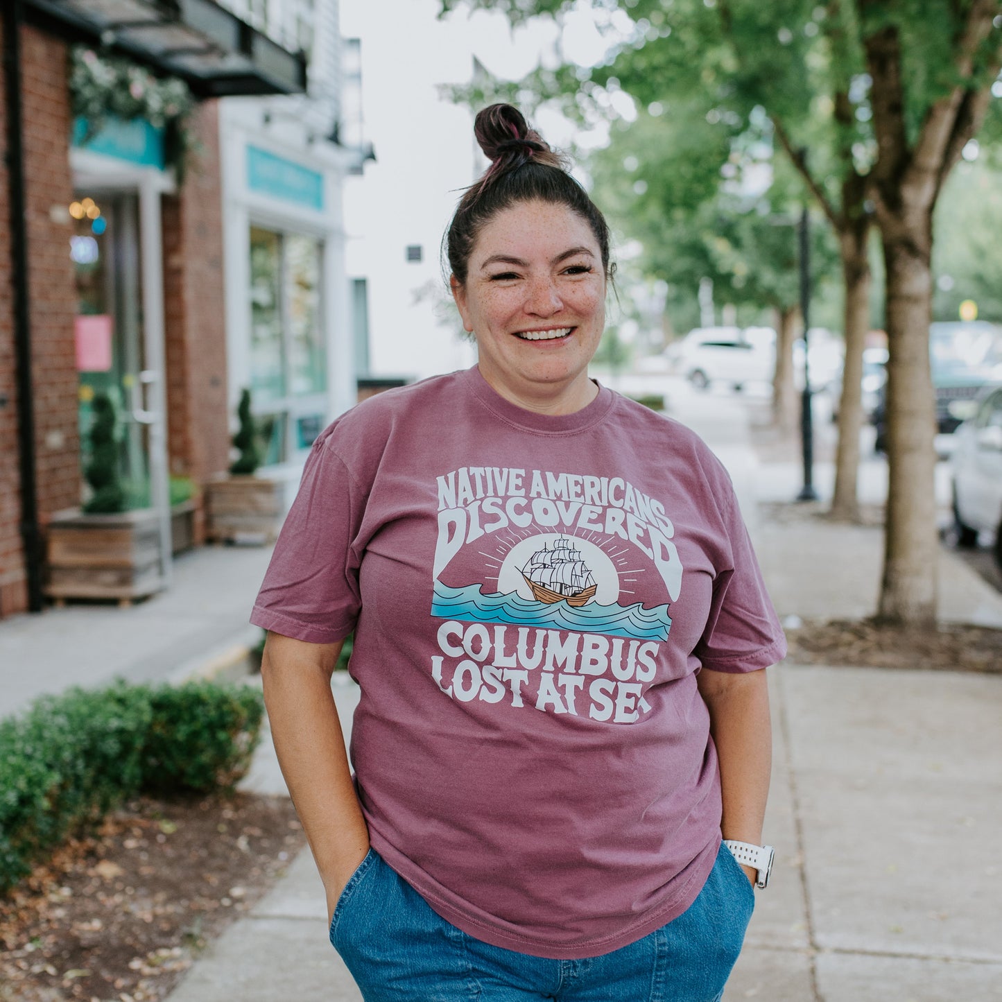 Person wearing a purple t-shirt with a graphic design on a sidewalk.