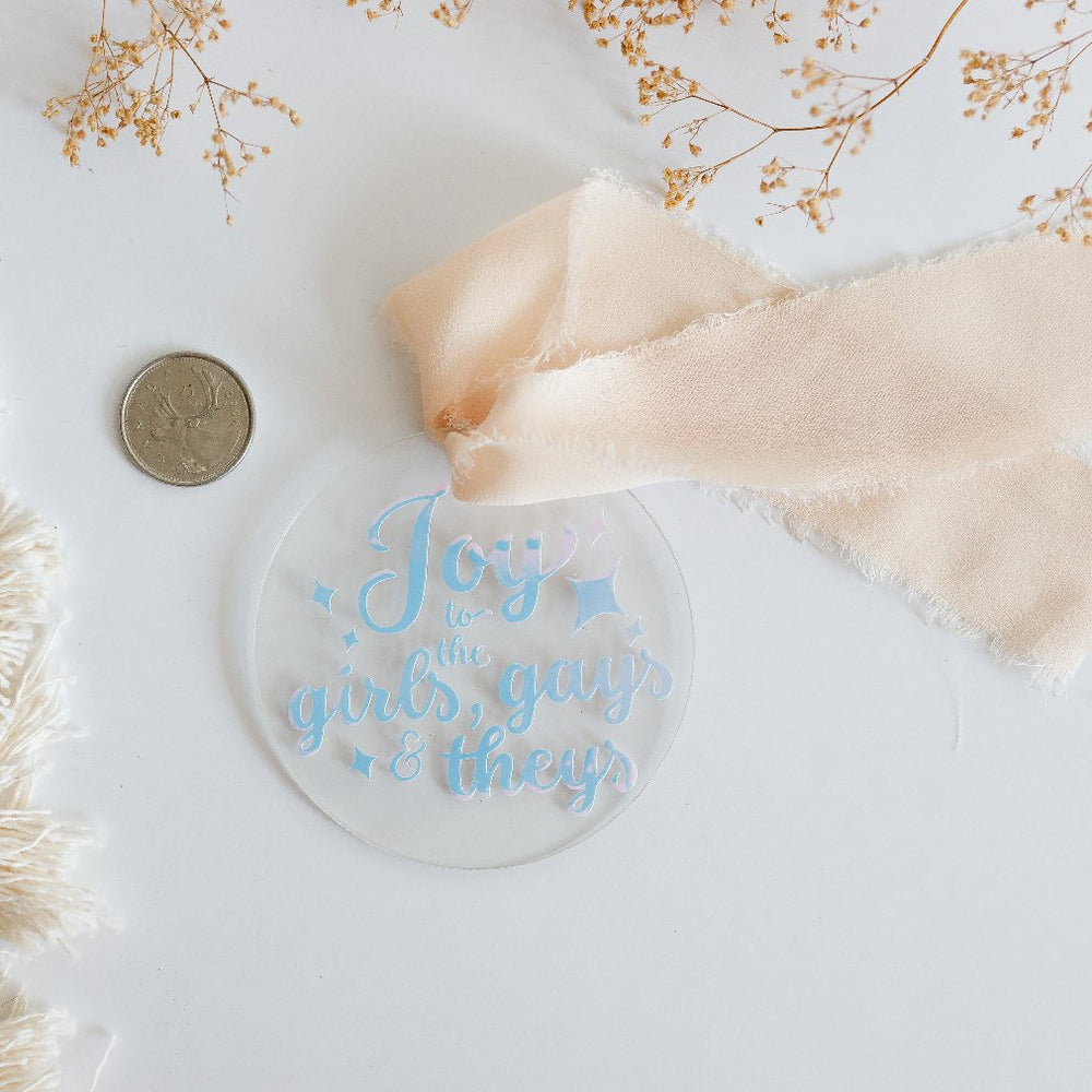 
                  
                    Decorative glass ornament with 'Joy to the world' text, ribbon, and macrame decor on a light background
                  
                