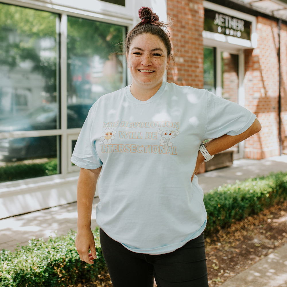 
                  
                    Person wearing a light blue t-shirt with text, standing in front of Aether Studio building.
                  
                