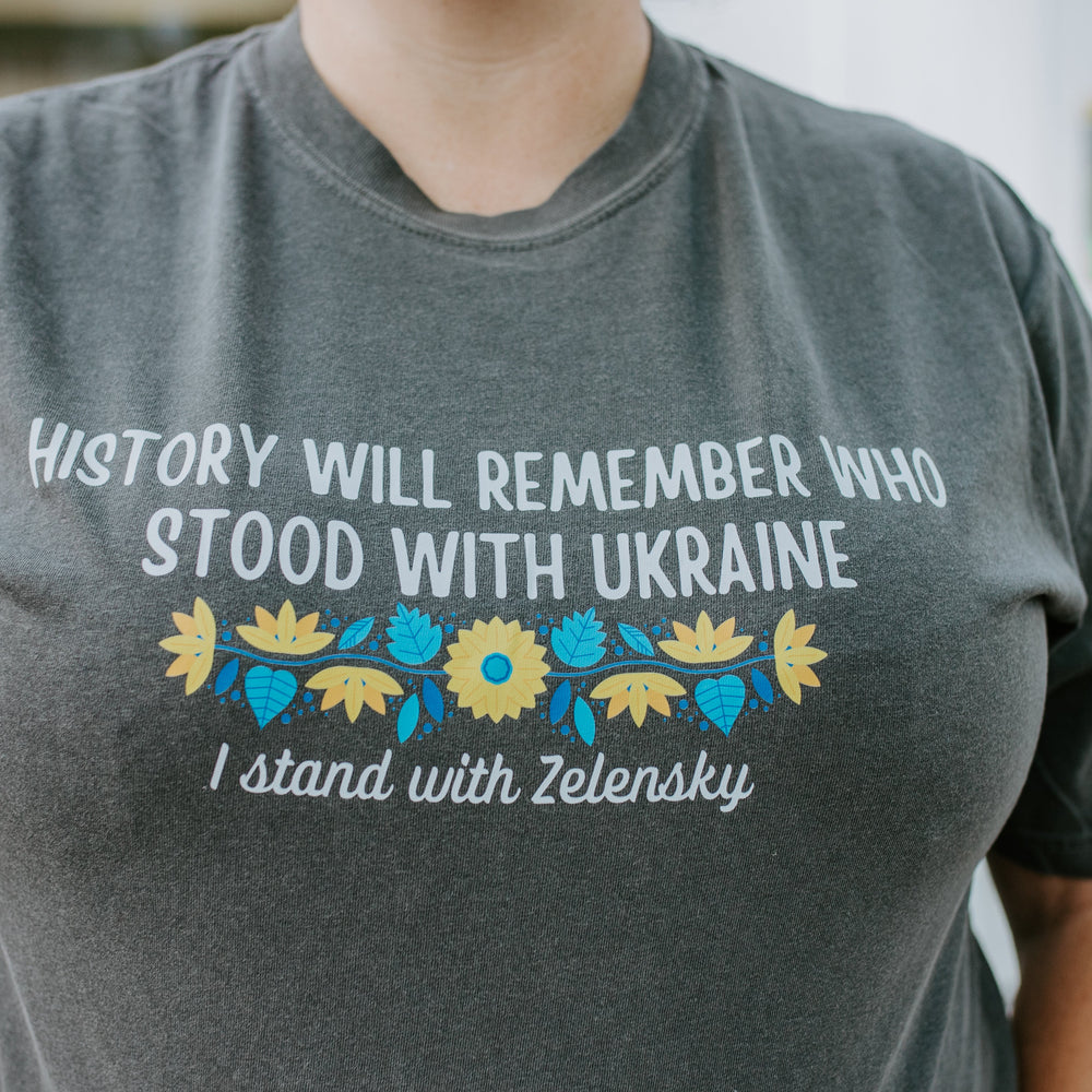 Person wearing a gray t-shirt with a message supporting Ukraine and Zelensky.