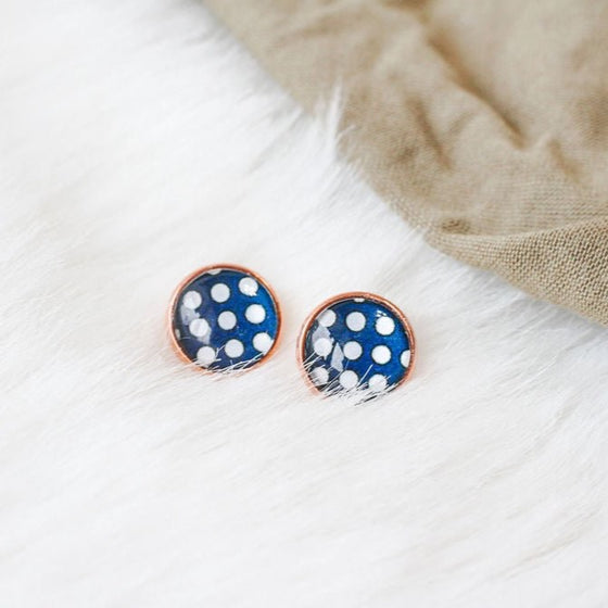 Stylish rose gold stud earrings with lead-free setting, showcasing classic polka dot charm against a vivid blue background, gracefully positioned on a clean white backdrop. Elevate your look with chic navy sophistication and timeless rose gold accents in these fashionable stud earrings.